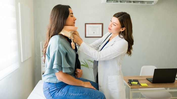 Doctor fitting a neck brace to a patient